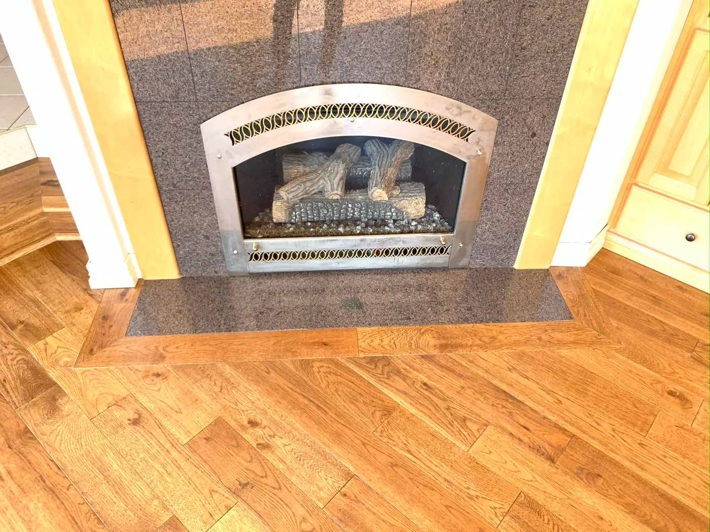 Angled oak plank flooring laid up to a tiled fireplace surround in a Tulsa metro home