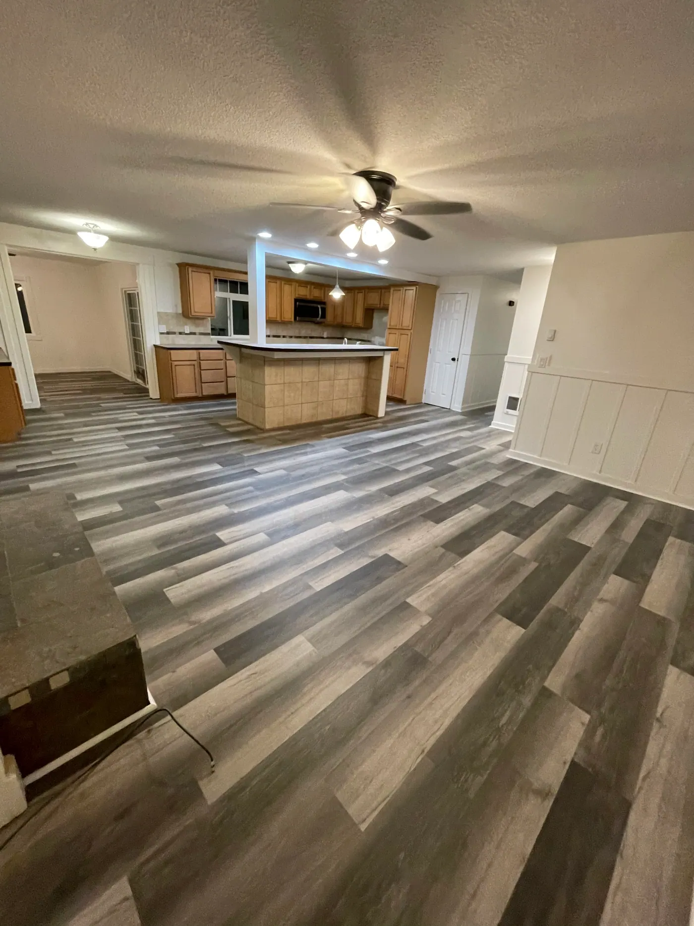 Gray plank flooring running through an open living and kitchen area in a Tulsa, OK home