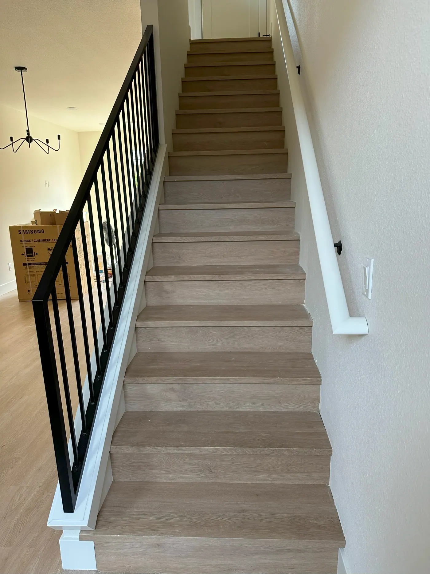 Light stair treads with white risers and a black metal railing in a Tulsa, OK home