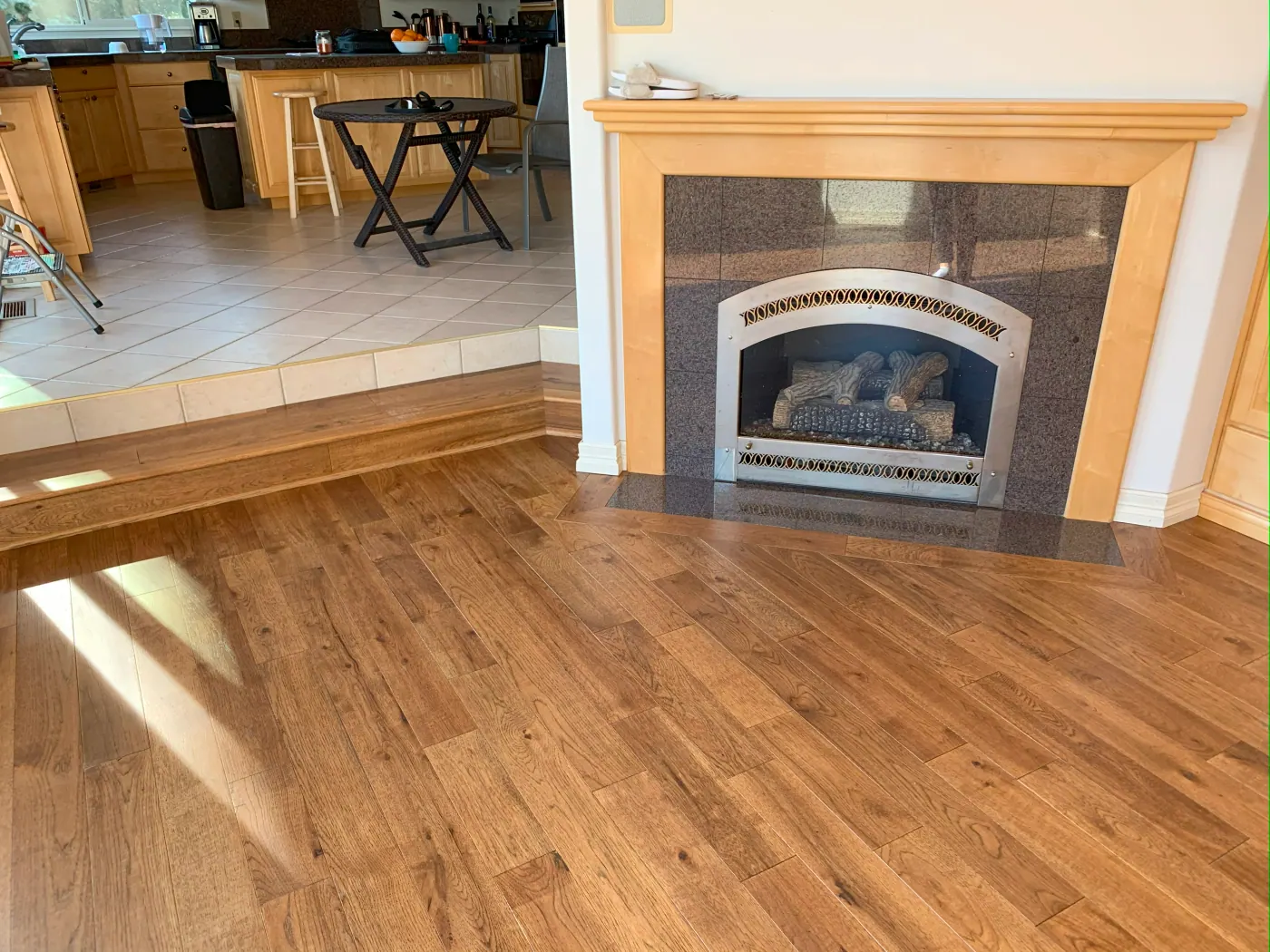 Oak hardwood flooring between a fireplace and kitchen in a Tulsa home