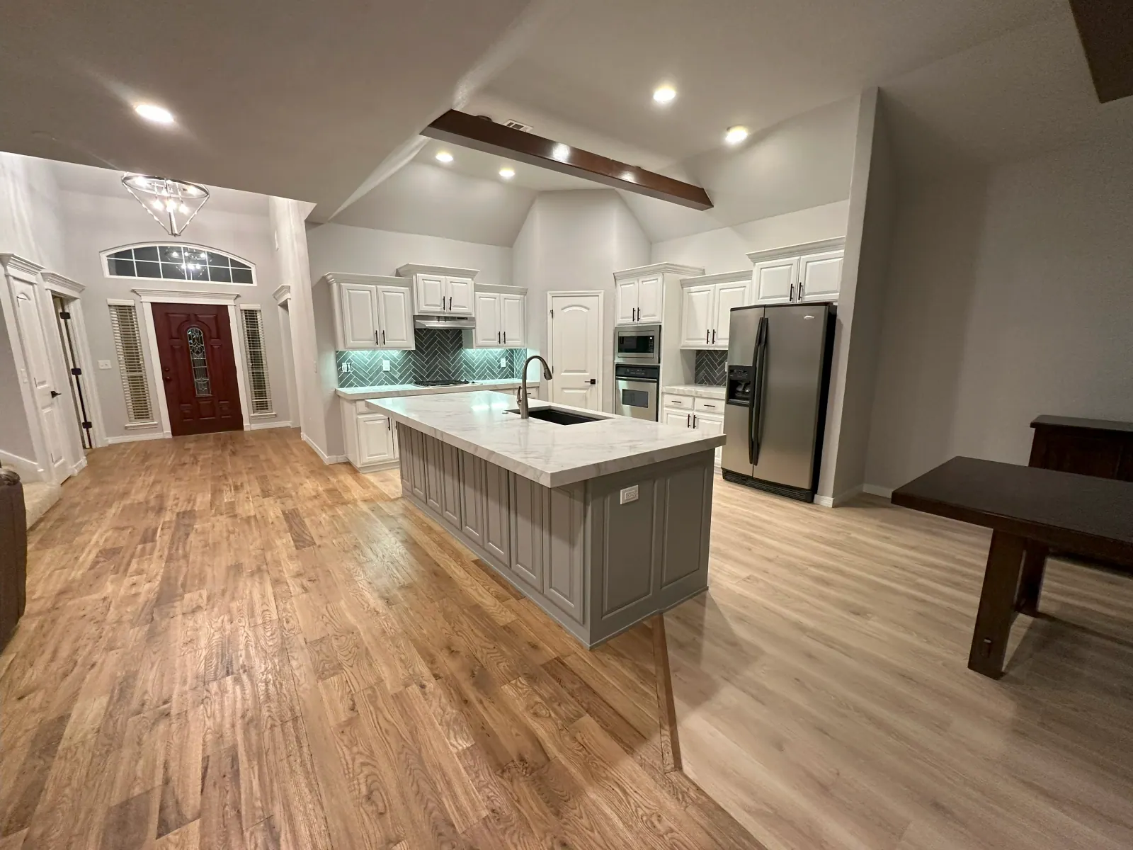 Plank flooring in a white kitchen with exposed ceiling beams in a Tulsa metro home